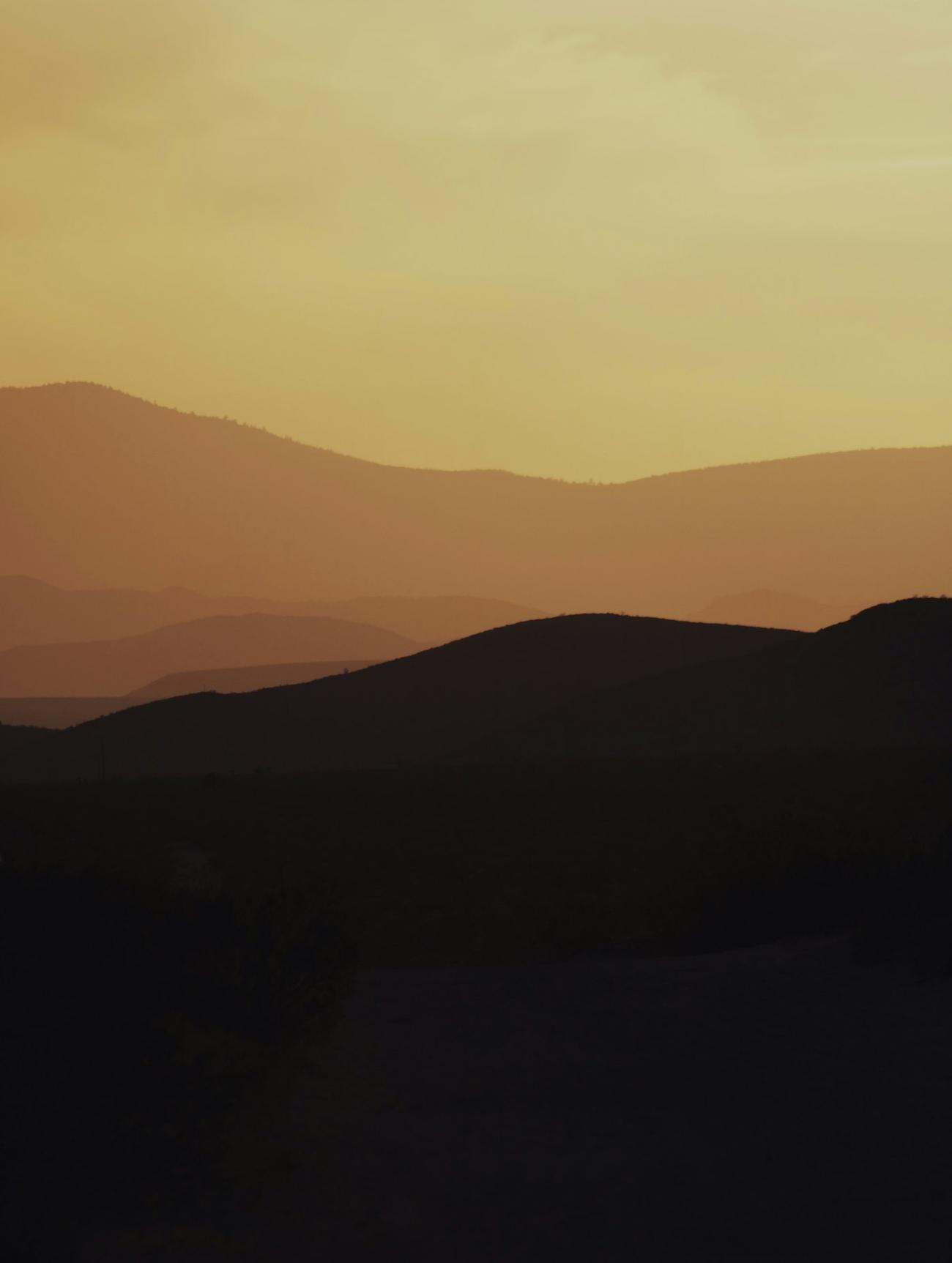 Layered mountain ridges fading into warm haze